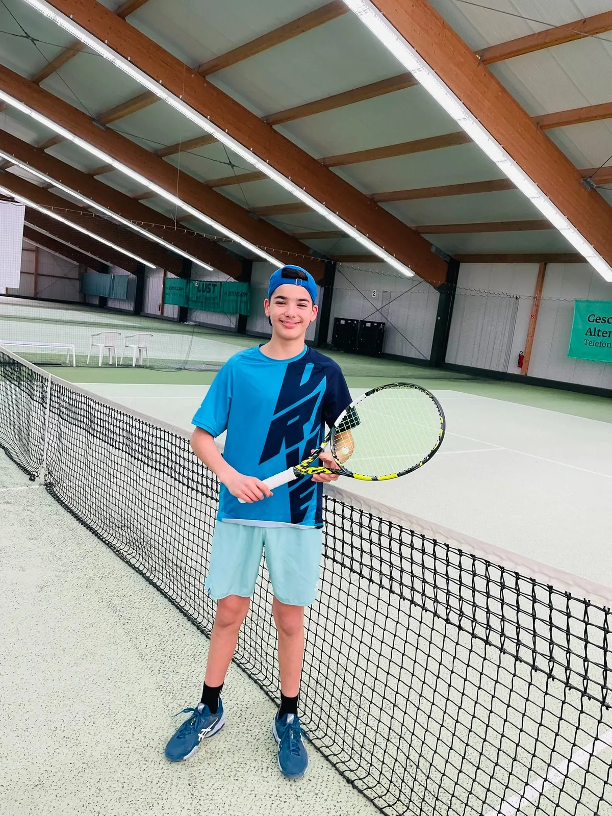 Junger Spieler mit Schläger am Netz in der Tennishalle Zwenkau